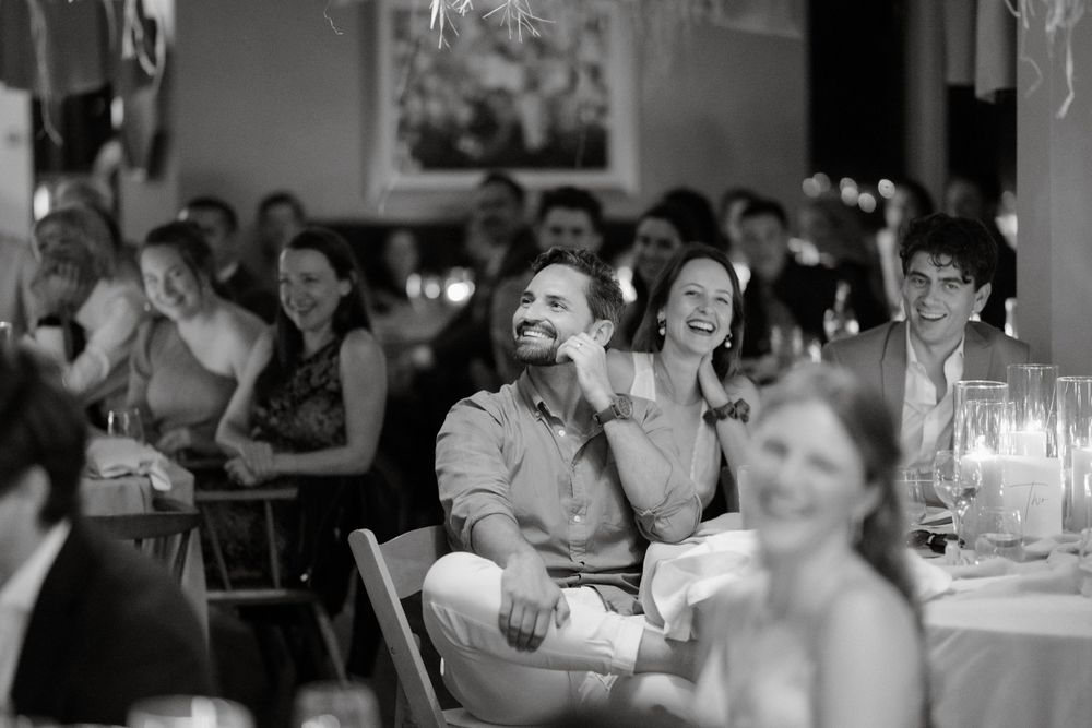 Black and white photo capturing joyful laughter during a dinner reception.