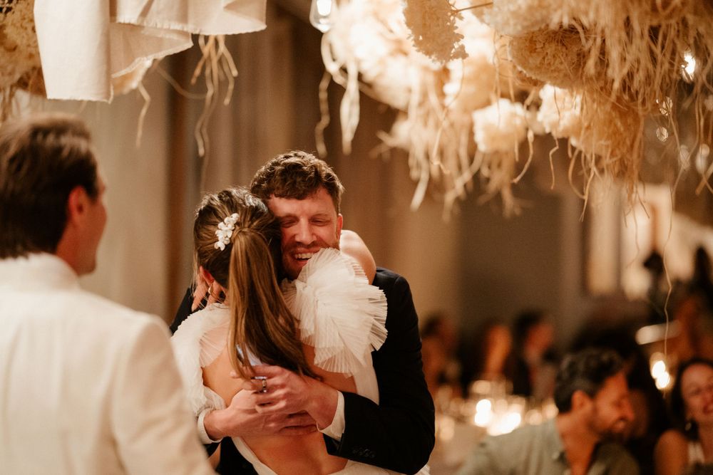 A couple sharing an intimate dance moment under hanging dried floral decorations.