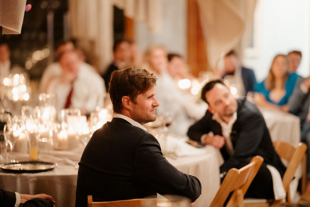 Candlelit wedding reception dinner with guests seated at elegantly decorated tables.