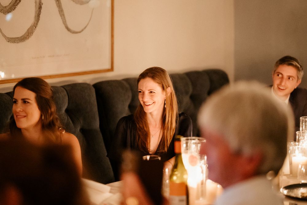 Warm-toned candid photo of dinner guests enjoying conversation at an evening gathering.