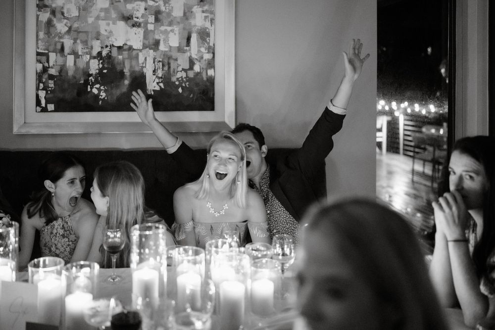 Black and white photo of wedding guests celebrating with candles on dining tables.