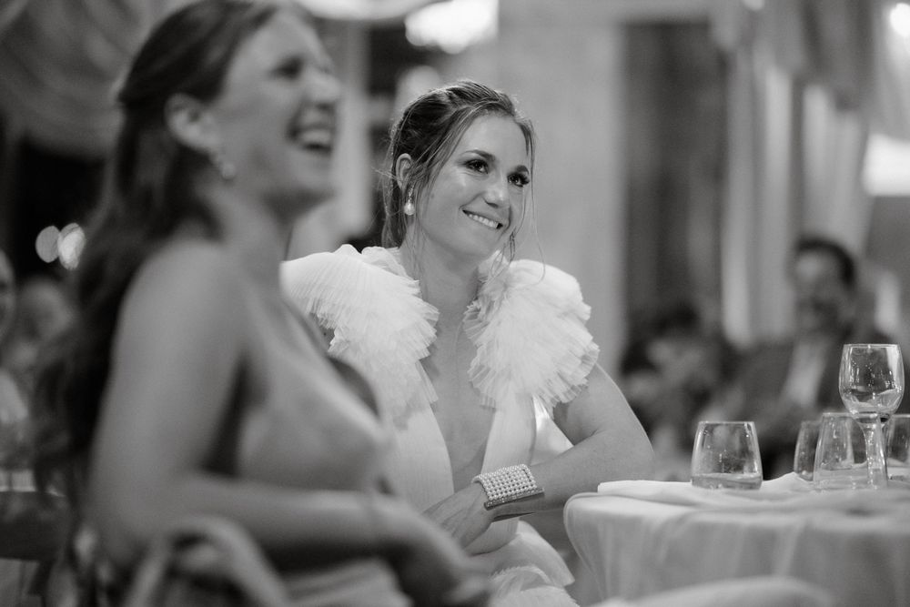 Candid black and white photo of reception guests enjoying dinner and conversation.