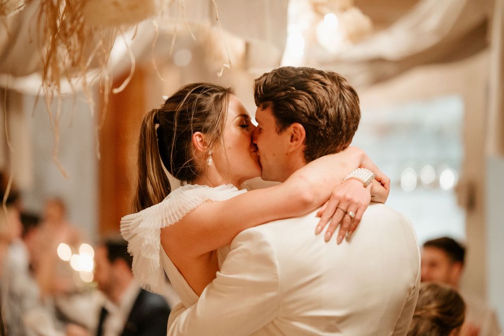 Romantic first dance kiss between newlyweds at wedding reception.