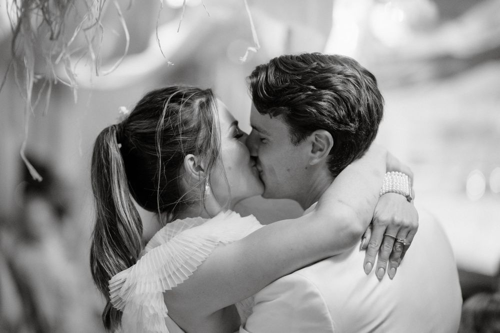 Black and white romantic wedding kiss captured in intimate moment.