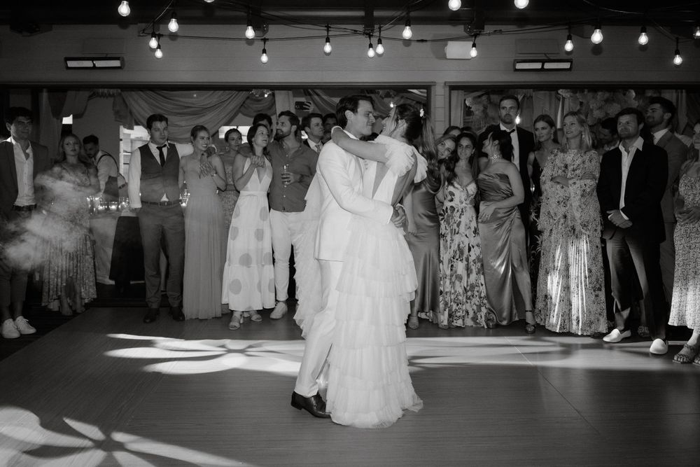 Classic black and white photo of a couple's first dance surrounded by wedding guests.