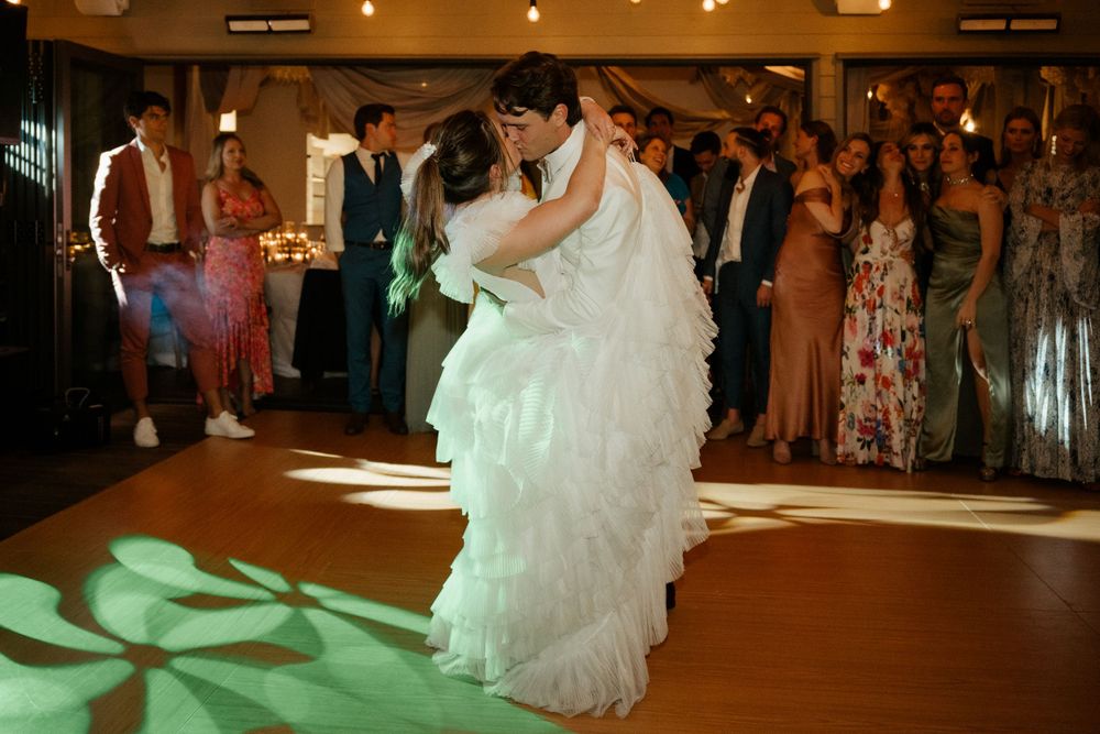 Couple sharing their first dance at wedding reception with decorative lighting effects.