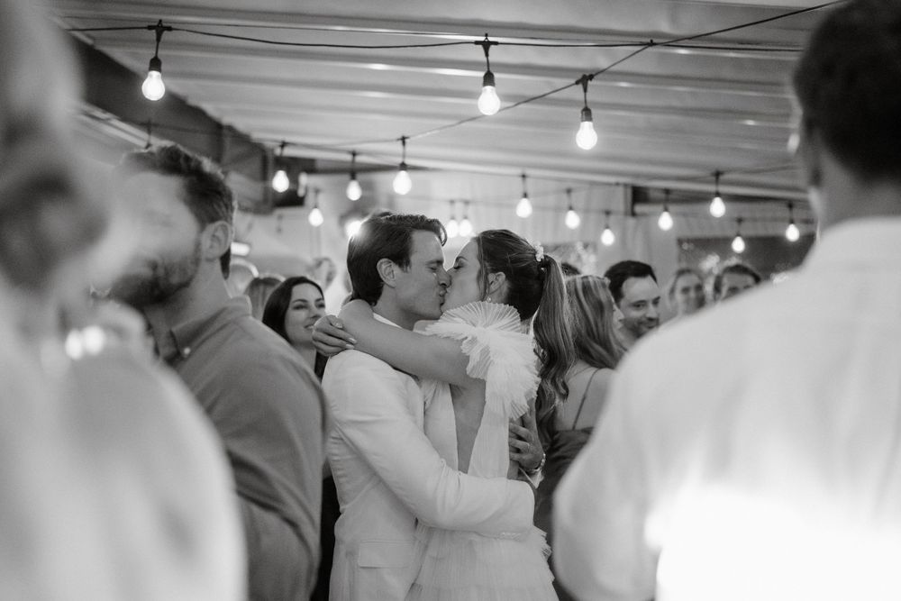 Black and white photo of couples slow dancing during an intimate indoor reception.