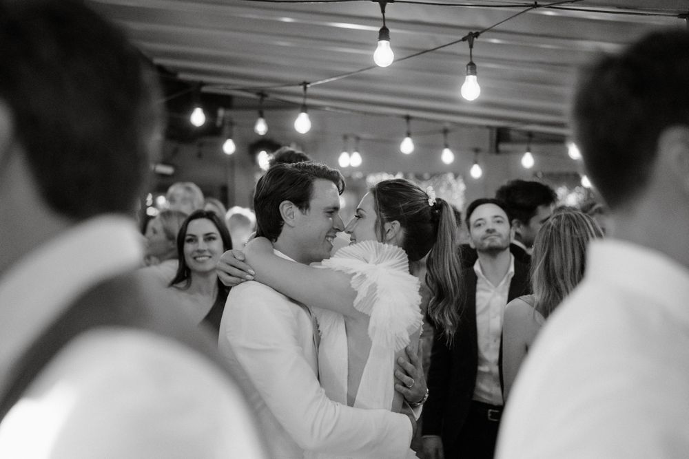 Black and white photo of a couple's first dance surrounded by wedding guests.