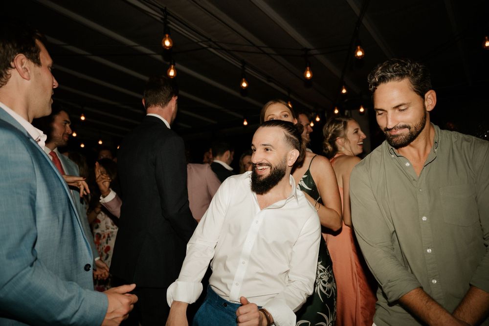 Wedding guests socializing and mingling during an evening reception under ambient lighting.