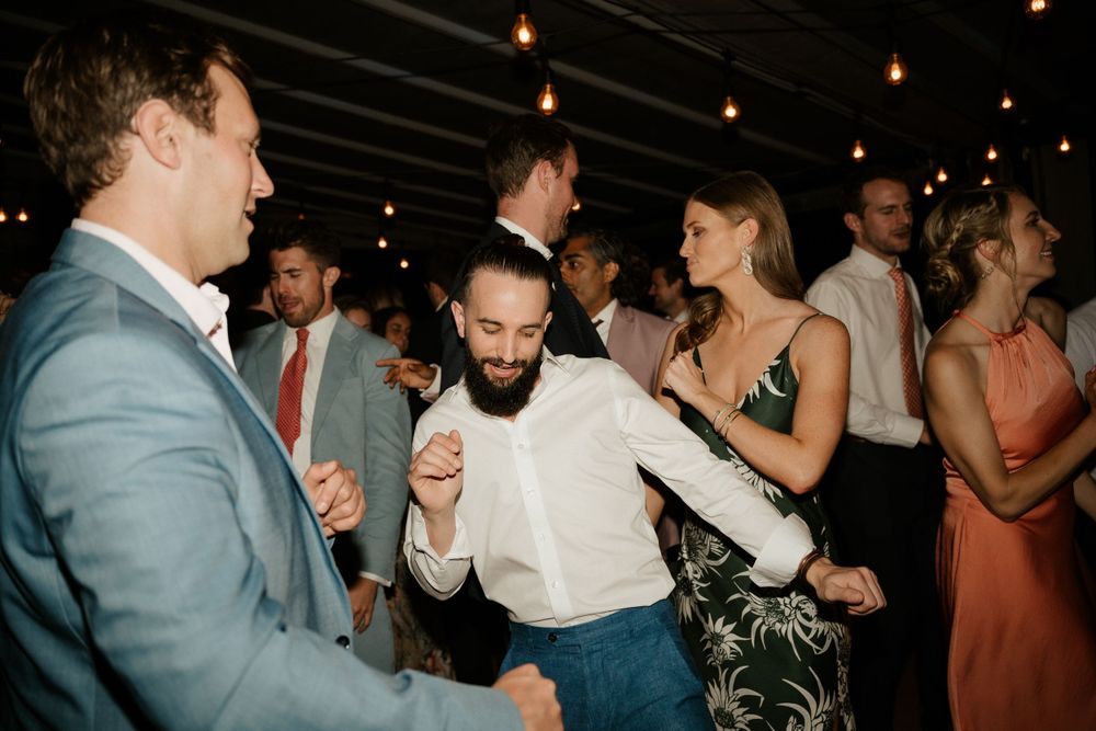 Wedding guests dancing and celebrating at a lively indoor reception.