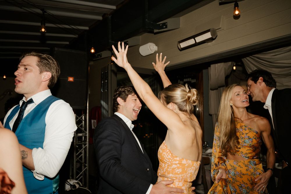 Wedding reception dance floor with guests celebrating under string lights.
