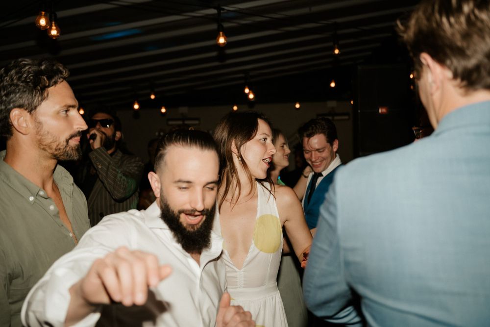 Candid shot of wedding reception guests dancing and celebrating on the dance floor.