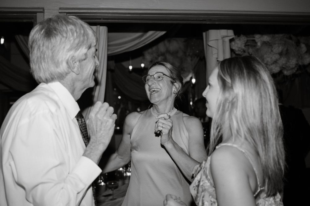 Black and white candid of guests singing and celebrating at evening party.