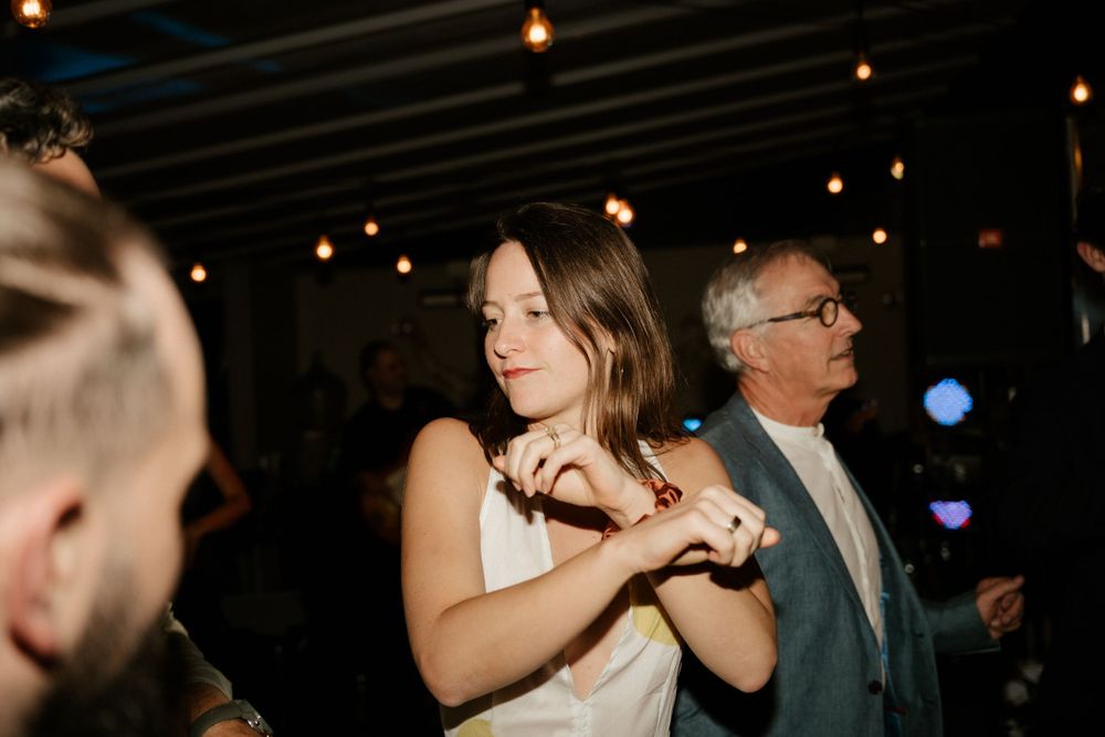 Wedding guests dancing and enjoying themselves under dimly lit ceiling.