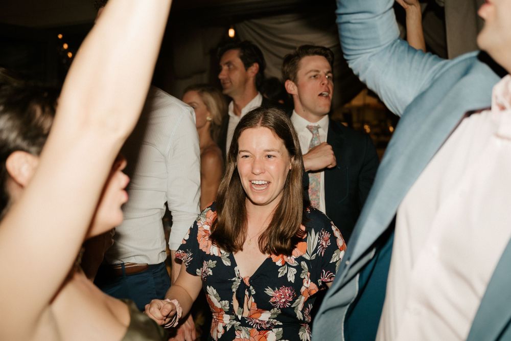Energetic dance party with guests celebrating under dark ceiling beams.