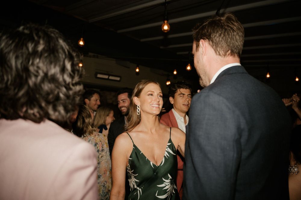 Guests mingling and conversing at an evening party under dim lighting.