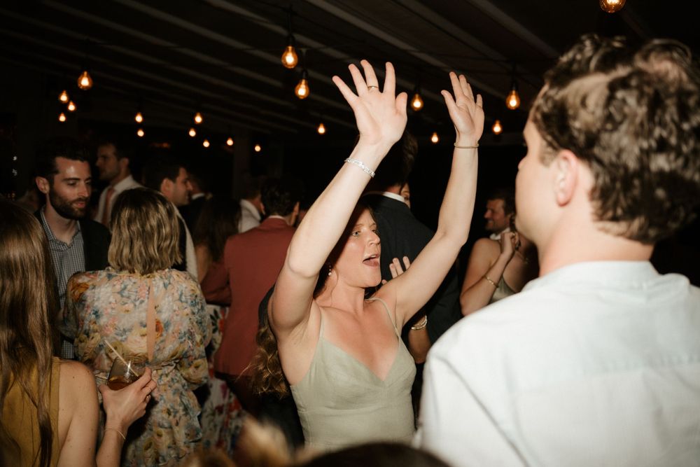 Lively dance floor scene with guests celebrating under dark ceiling with string lights.