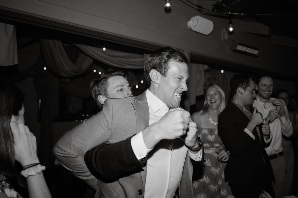 A black and white photo capturing energetic dancing at a wedding reception.