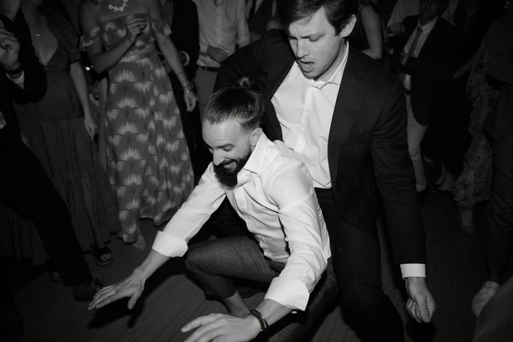 Black and white photo of wedding guests dancing energetically at reception.