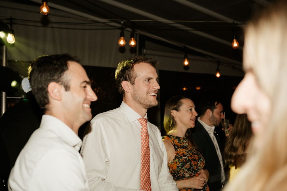 Candid reception photo of guests laughing and enjoying conversation at evening event.
