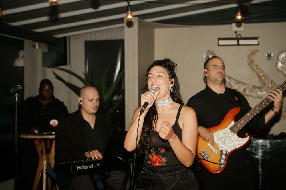 Live band performs at wedding reception with singer and guitarist on stage.
