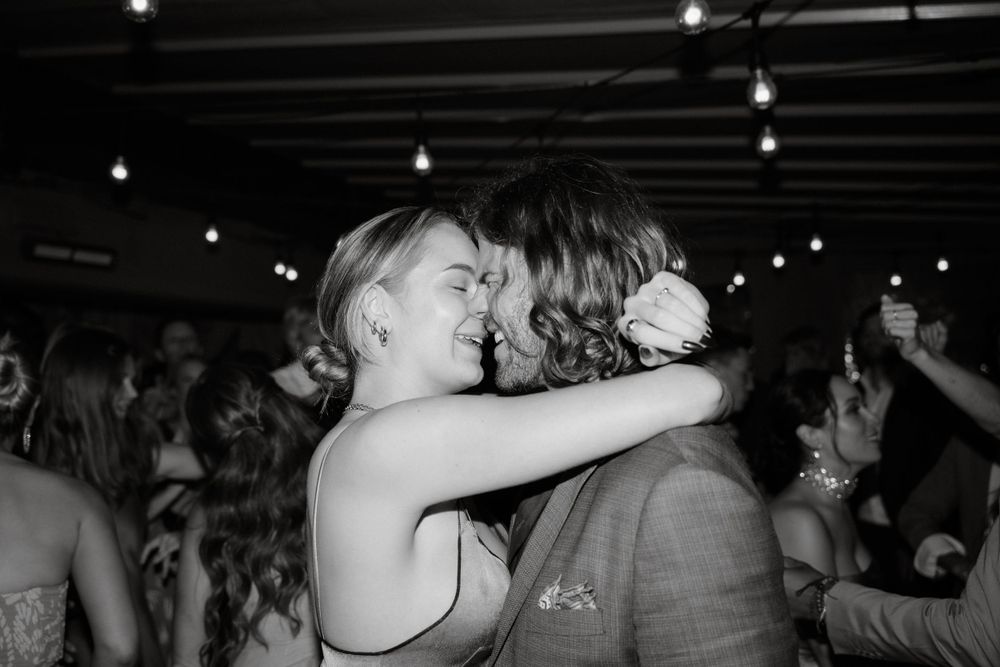 Intimate black and white photo of dancing couples at dimly lit reception.