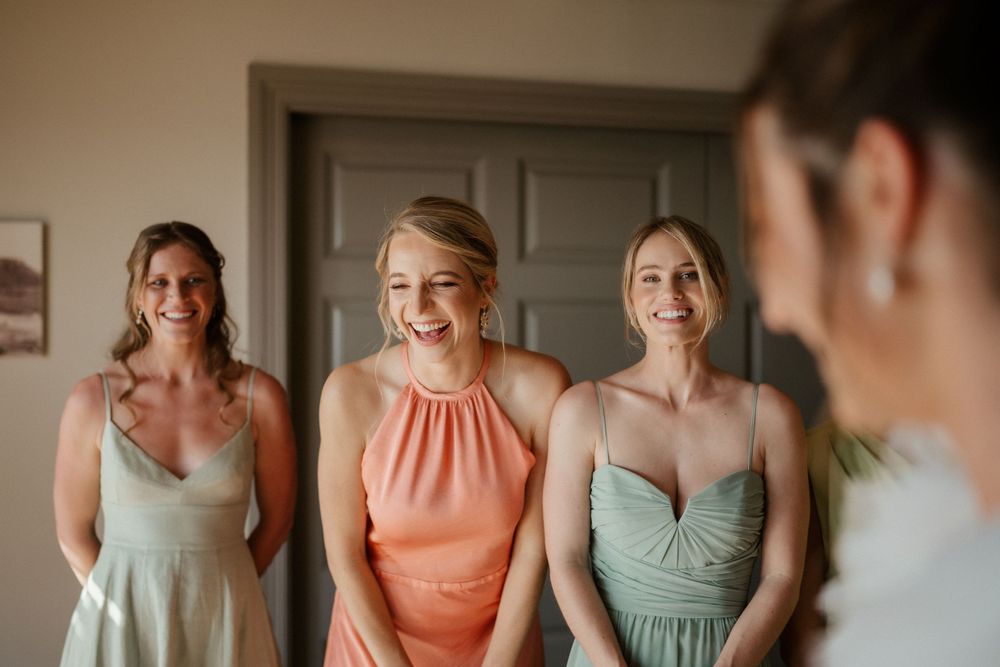 Wedding party members in pastel dresses gathered in preparation room.