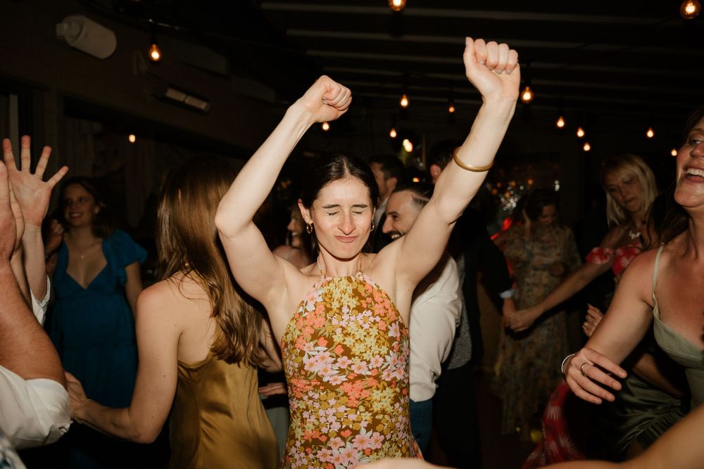 Wedding guest dances enthusiastically with raised arms at a lively reception party.