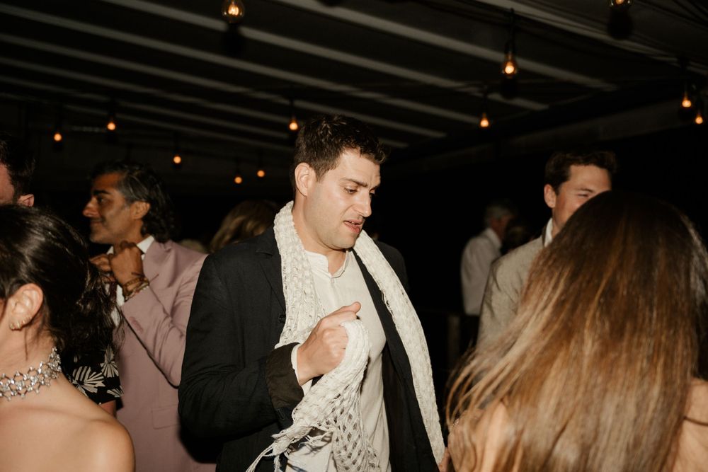Party guests dancing and enjoying themselves under dim lighting at an evening celebration.