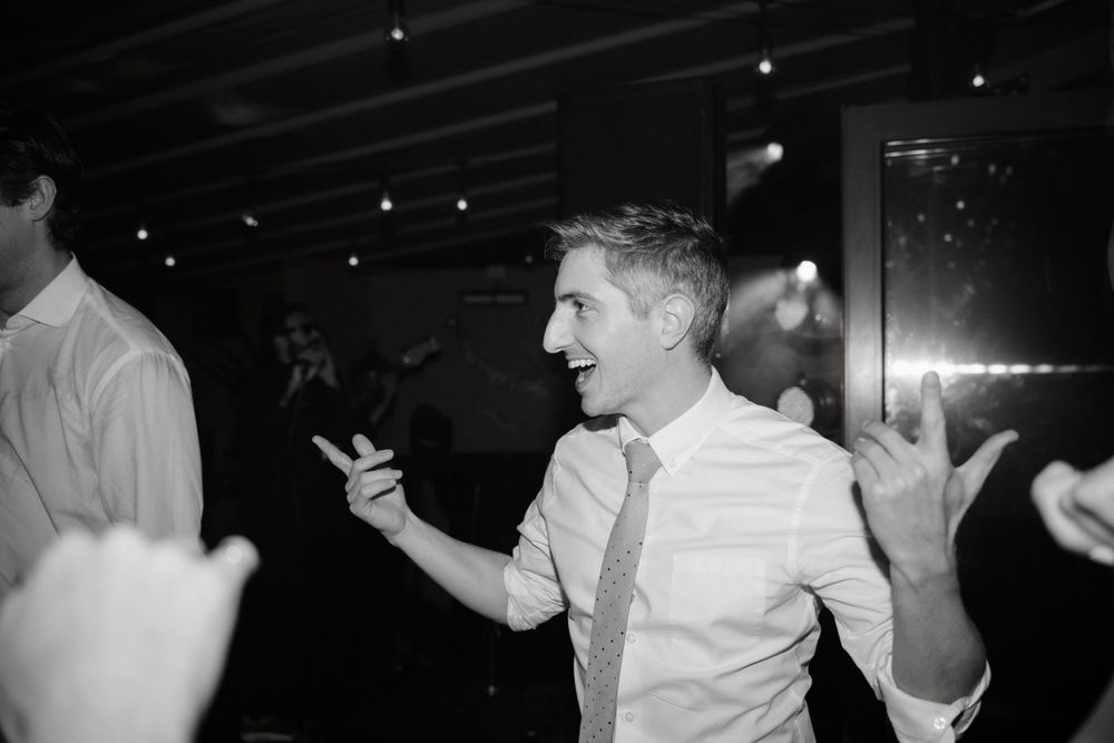 A black and white capture of wedding guests dancing enthusiastically at the reception.