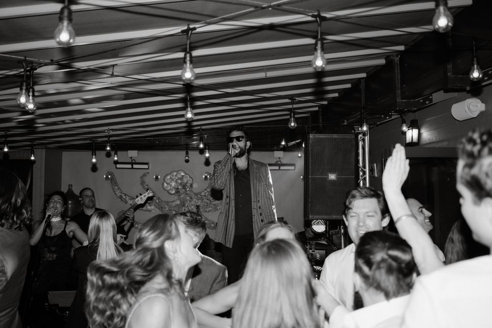 Crowd dancing at a concert with hands raised in black and white photography.