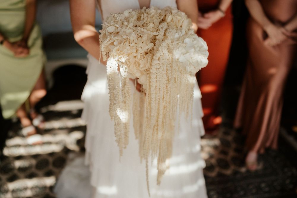 Close-up detail shot of intricate beige lace and fabric on a wedding dress in natural light.