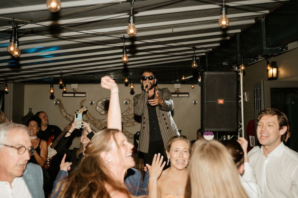 Energetic dancing and celebration at a wedding reception with overhead lighting.