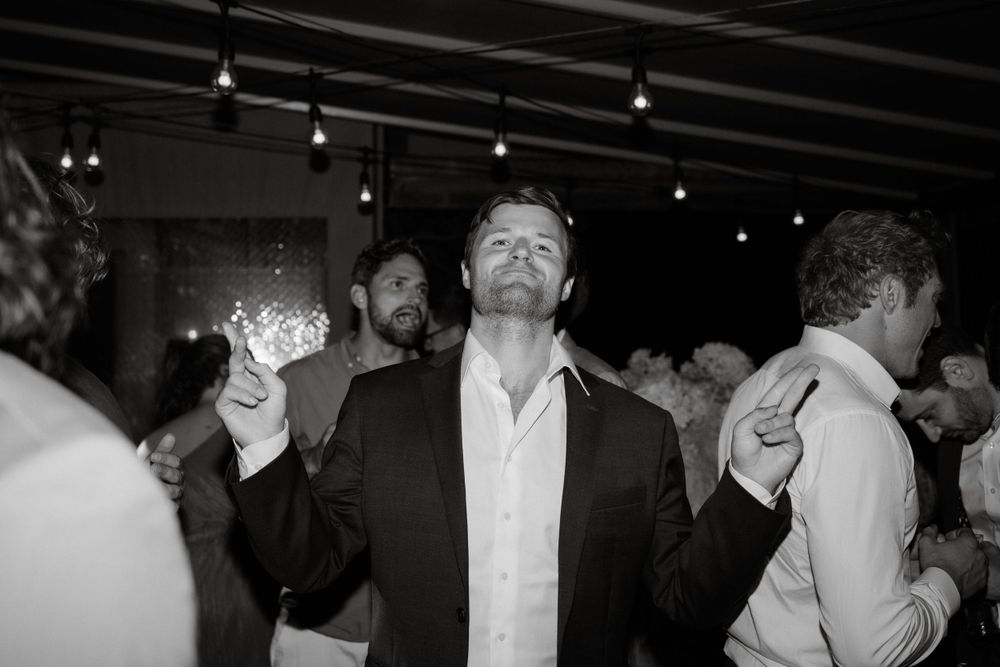 Black and white photo of guest celebrating on dance floor at wedding reception.