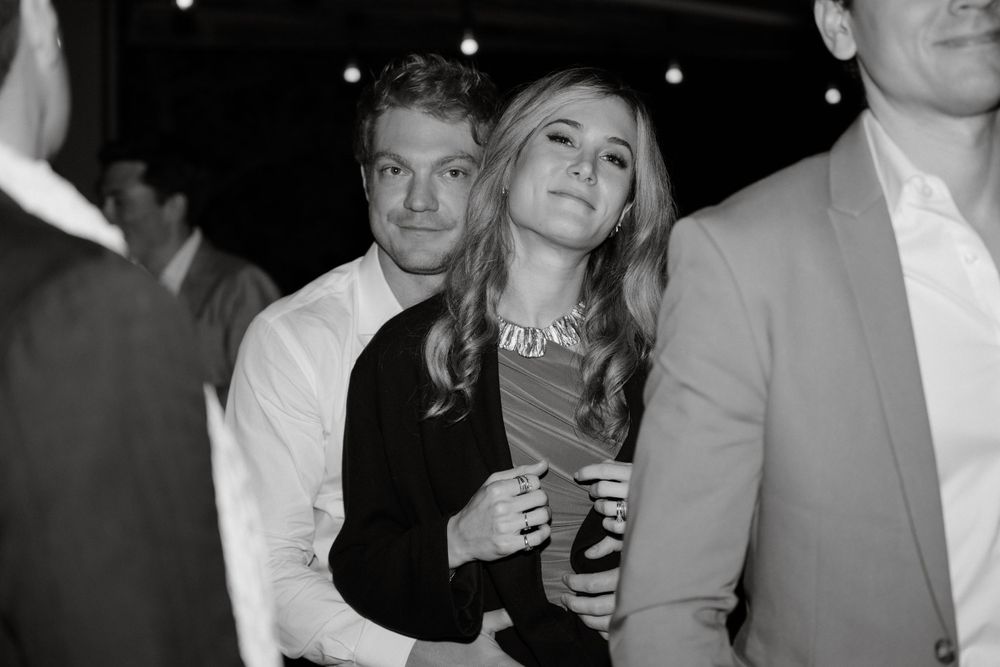 Black and white candid photo of guests mingling at an evening event.