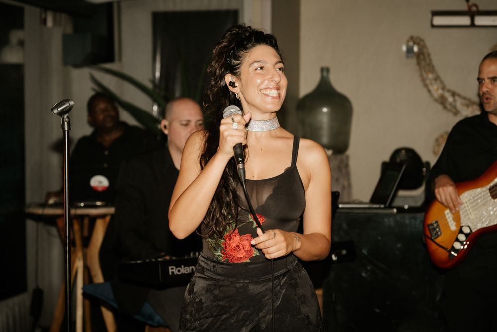 Live band performs at a wedding reception with singer and guitarist on stage.