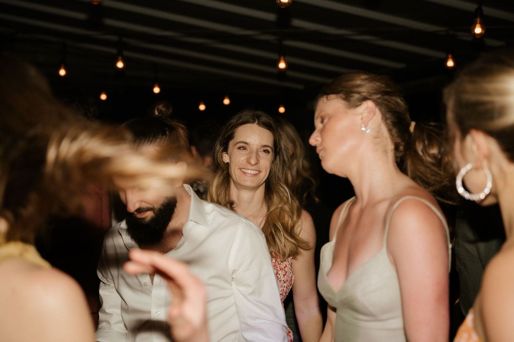 Wedding guests dancing and socializing under string lights at an evening celebration.