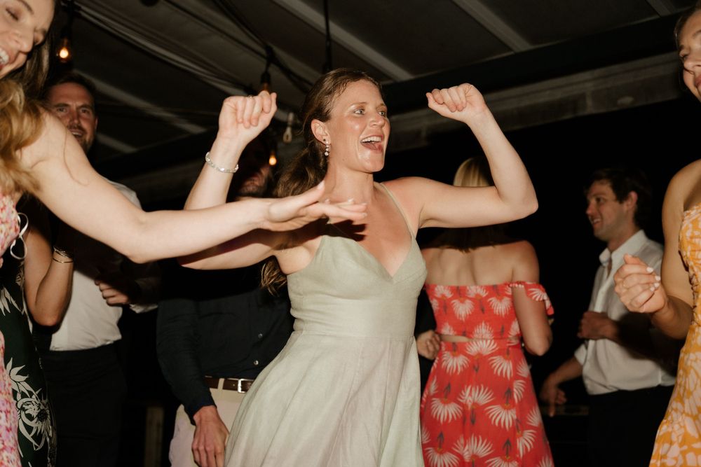 A dancing celebration at a wedding reception with people moving enthusiastically on the dance floor.