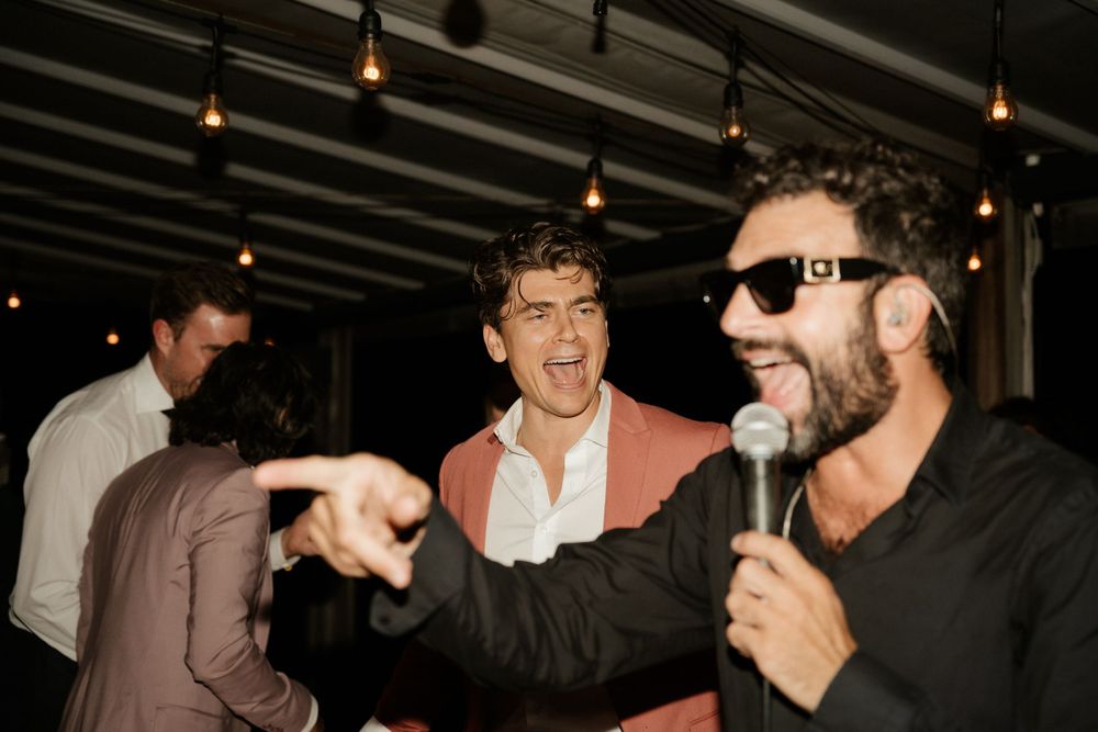 Wedding guests enjoying entertainment with microphone and animated gestures at reception.