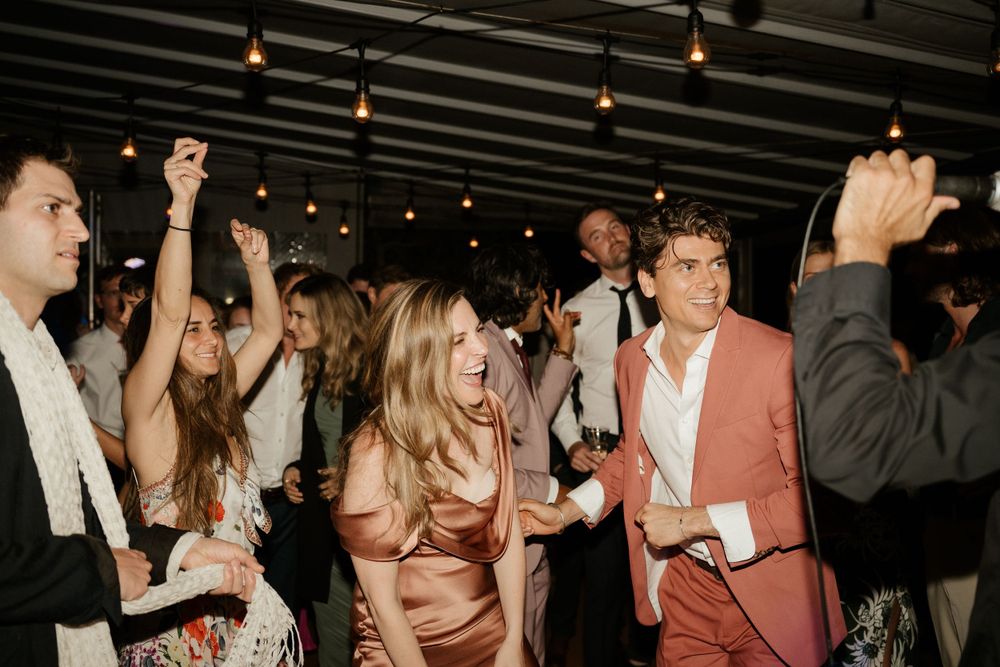 People dancing and celebrating at a party under warm lighting.
