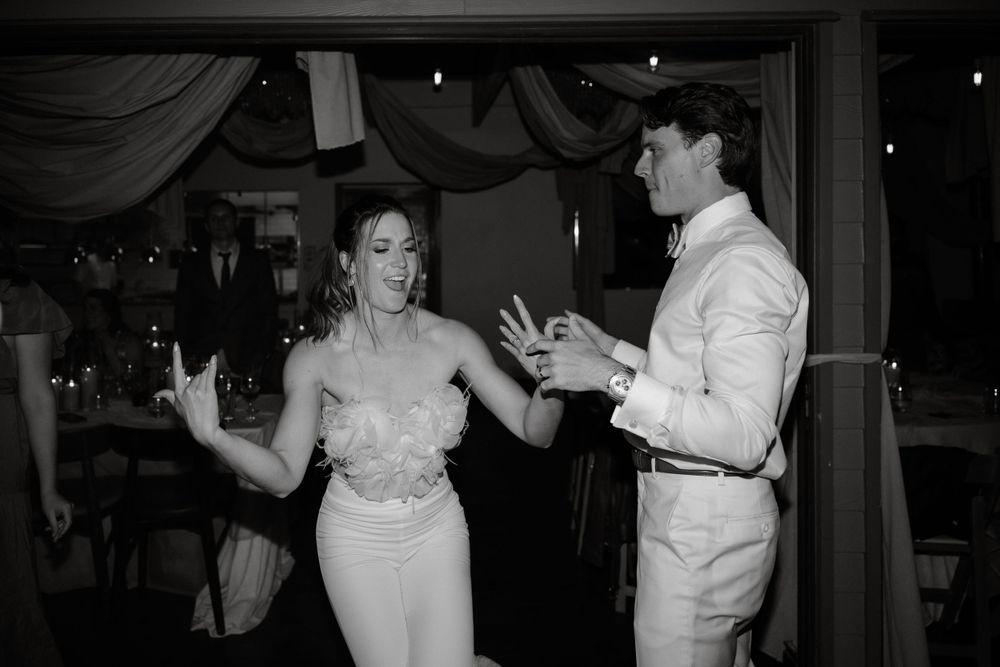 Black and white photo of couple dancing and laughing at wedding reception.