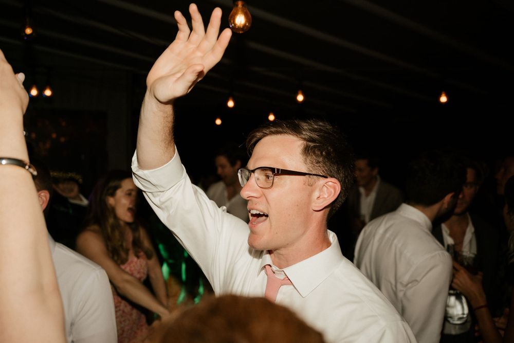 An enthusiastic guest dancing with raised arms during the wedding celebration.