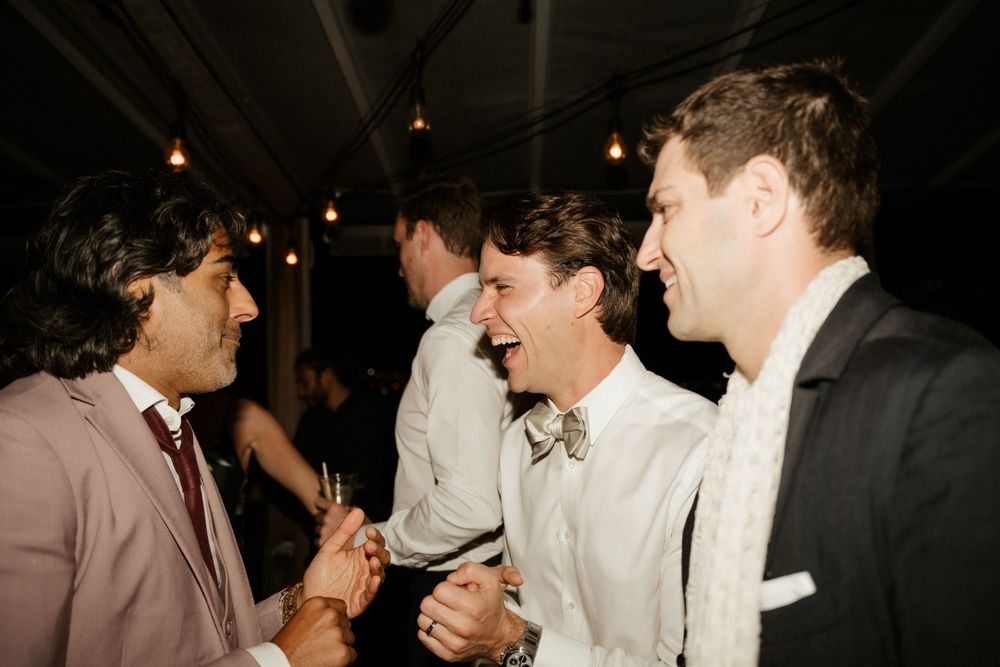 Group of formally dressed guests sharing laughs at an evening celebration.