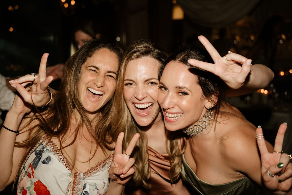 Friends celebrating together at a party showing peace signs and laughing.