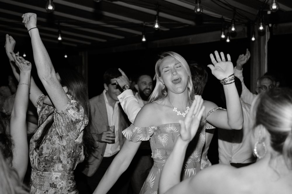 Black and white photograph of energetic dancing during wedding reception celebration.