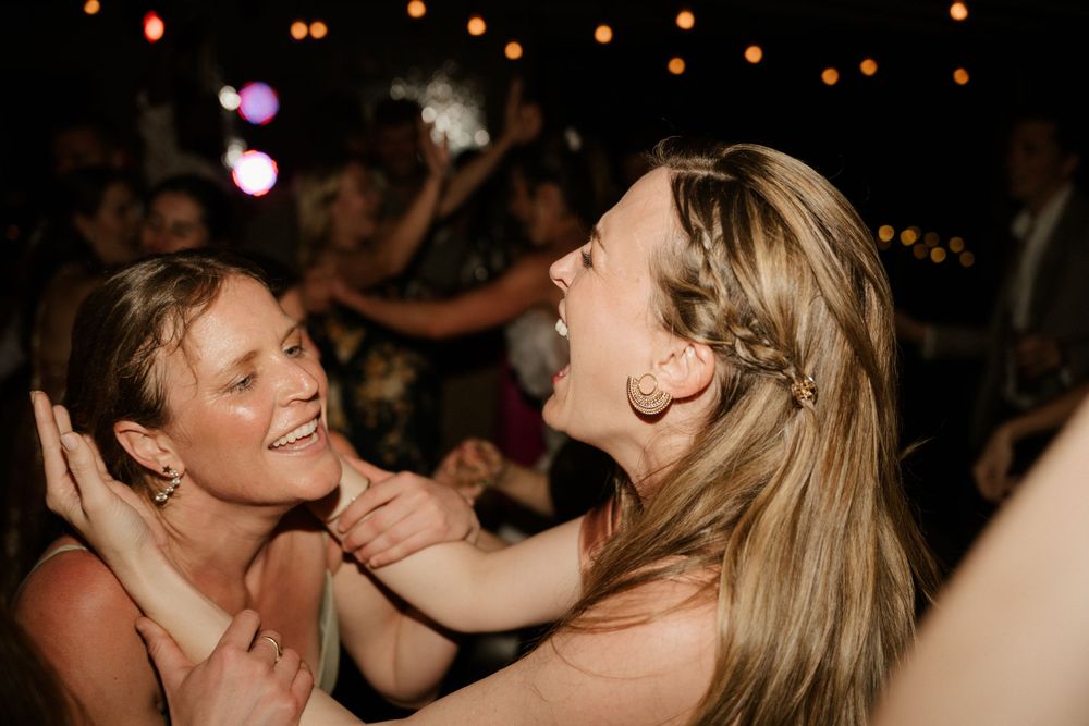 Two guests sharing a joyful laugh on a dimly lit dance floor.