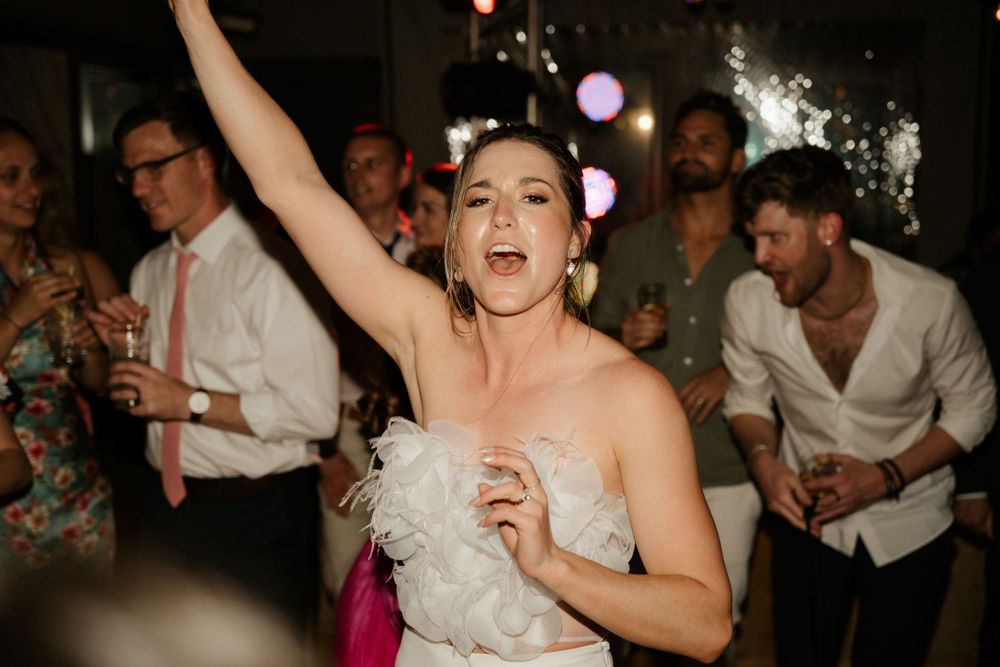 A joyful celebration on the dance floor with guests dancing under string lights.