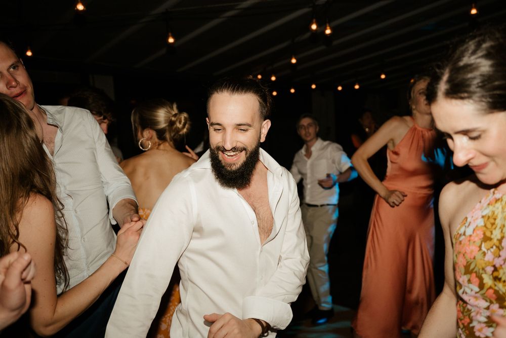Joyful wedding guests dancing at a reception under string lights.
