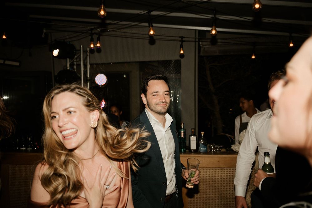 People dancing and enjoying themselves at a dimly lit party venue with hanging lights.