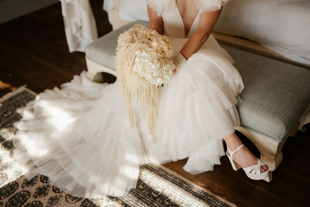 Detail shot of bride's elegant white tulle dress and sparkly shoes in natural window light.